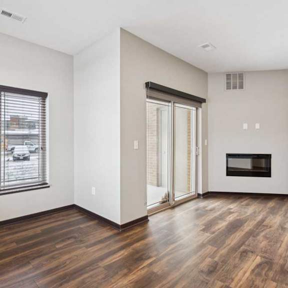 Thumbnail 8 of 19 A living room with hardwood-style flooring, an electric fireplace, and a sliding glass door to a patio, next to a dining area.