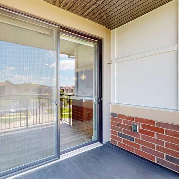 Thumbnail 7 of 27 A balcony with a sliding glass door and a screen door.