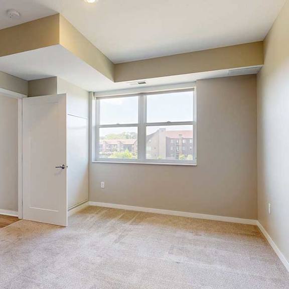 Thumbnail 19 of 27 A carpeted bedroom with a large window.