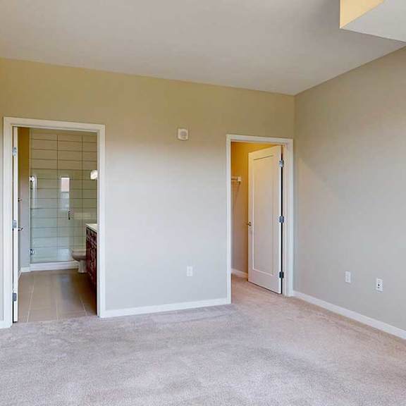 Thumbnail 20 of 27 A carpeted bedroom with and ensuite bathroom and walk-in closet.
