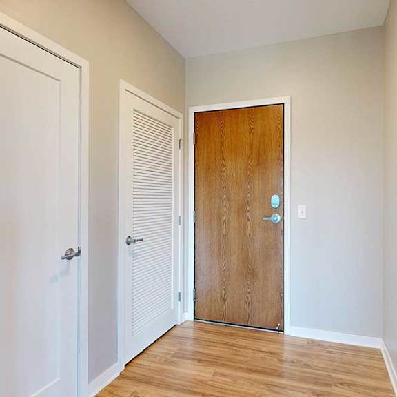 Thumbnail 2 of 27 A front entryway with a wooden front door and a closed laundry room door.