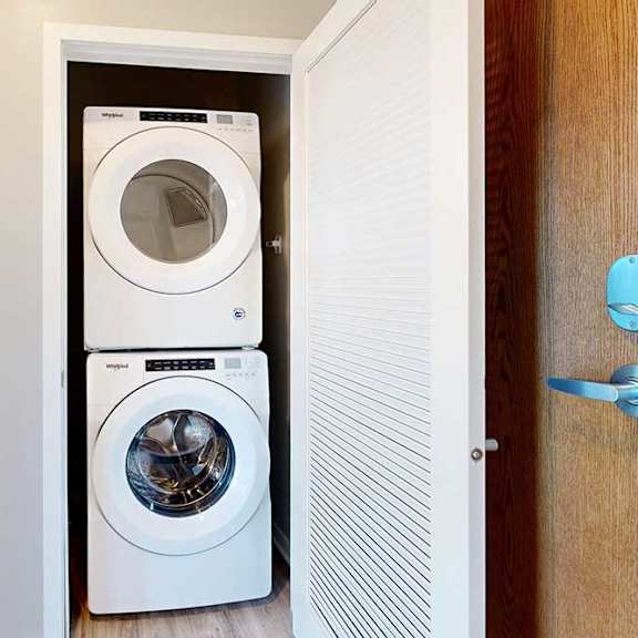 Thumbnail 3 of 27 A laundry closet in the front entryway with a stacked, front-loading washer and dryer.