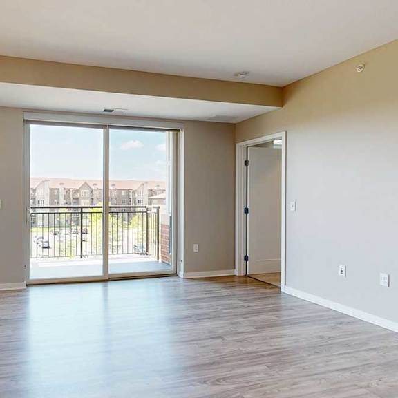 Thumbnail 18 of 27 A living room with hardwood-style flooring and a sliding glass door to the balcony.