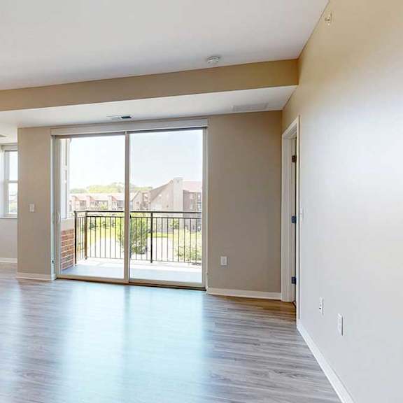 Thumbnail 5 of 27 A living room with hardwood-style flooring and a sliding glass door to the balcony.