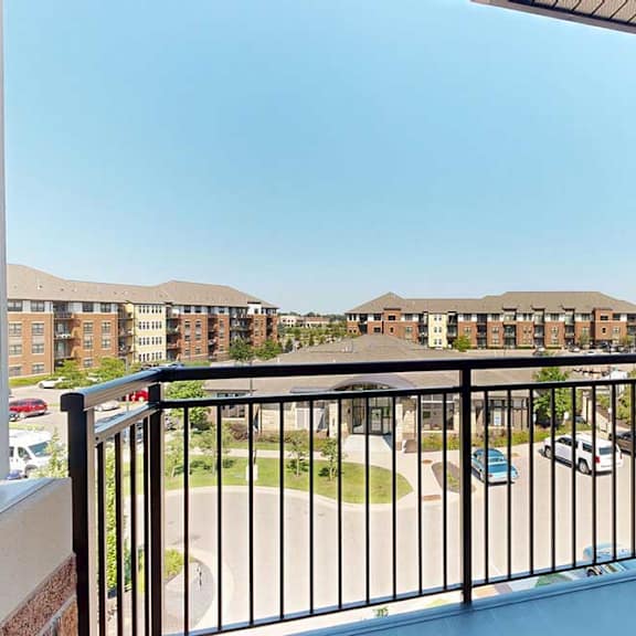 Thumbnail 8 of 29 A balcony with a metal railing and a view of the community.