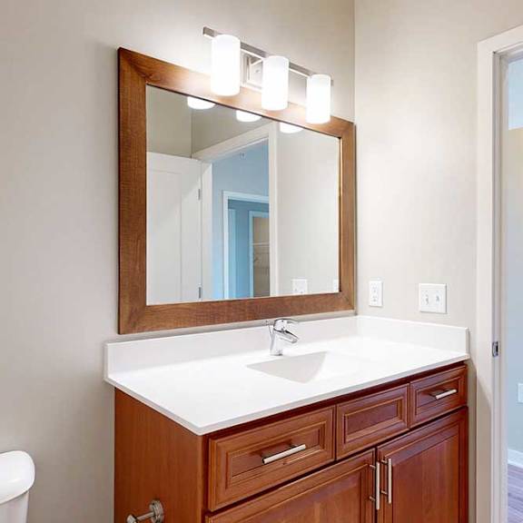 Thumbnail 28 of 29 A bathroom with a white quartz vanity sink, an oversized mirror, and overhead lighting.