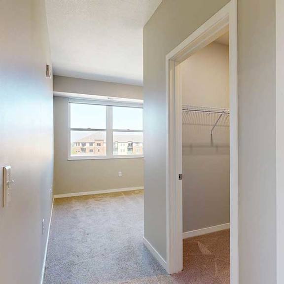 Thumbnail 19 of 29 A carpeted bedroom with a large window, an attached walk-in closet, and attached bathroom.