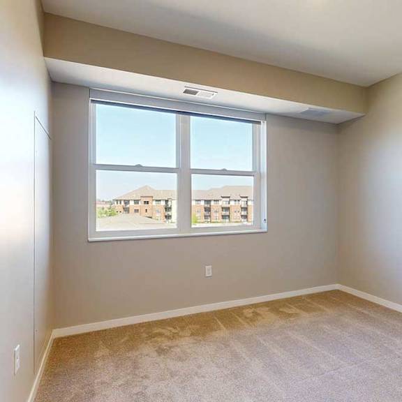 Thumbnail 20 of 29 A carpeted bedroom with a large window.