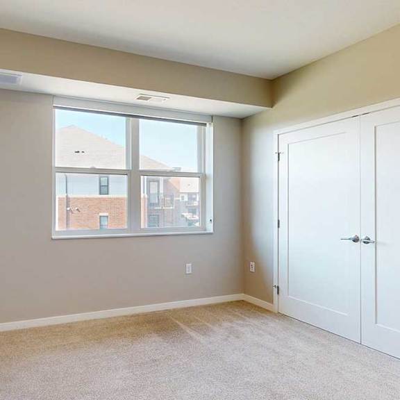 Thumbnail 27 of 29 A carpeted bedroom with a large window and a double-door closet.