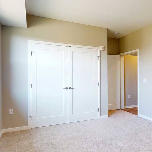 Thumbnail 25 of 29 A carpeted bedroom with a large window and a double-door closet.