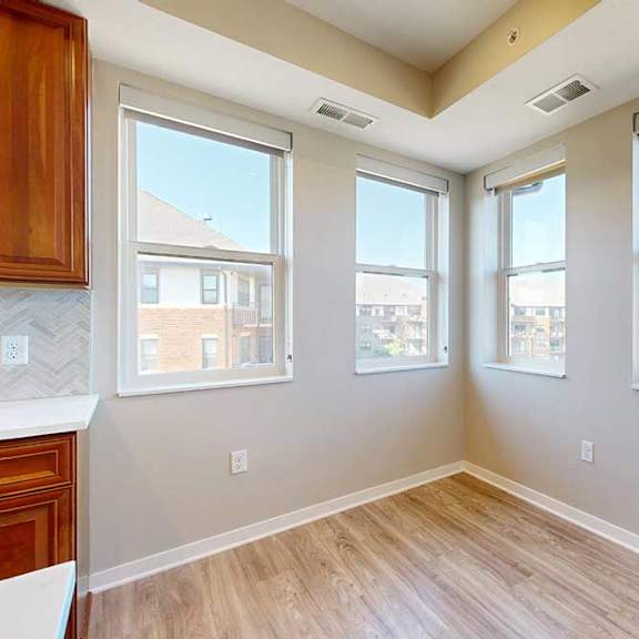 Thumbnail 14 of 29 A dining room with hardwood-style flooring, and several large windows for natural light.