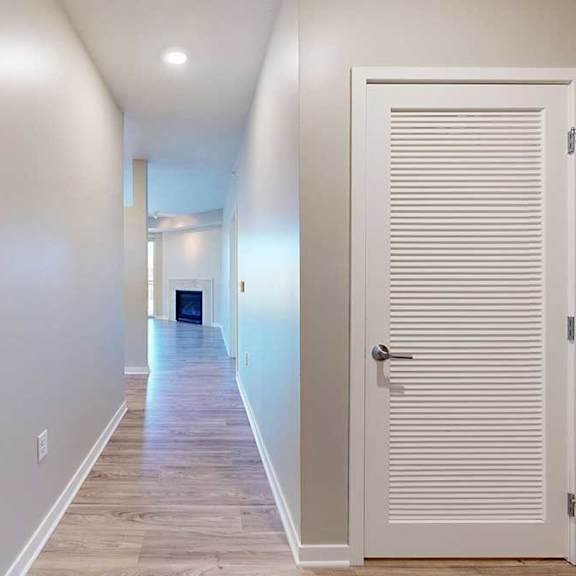 Thumbnail 4 of 29 A long hallway with a white door to the laundry room.