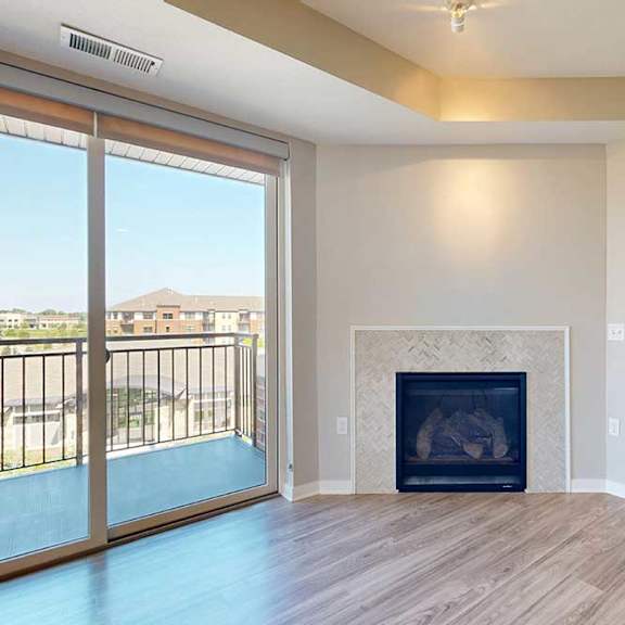 Thumbnail 6 of 29 A spacious living room with hardwood-style flooring, a built-in fireplace, and a sliding glass door to a balcony.