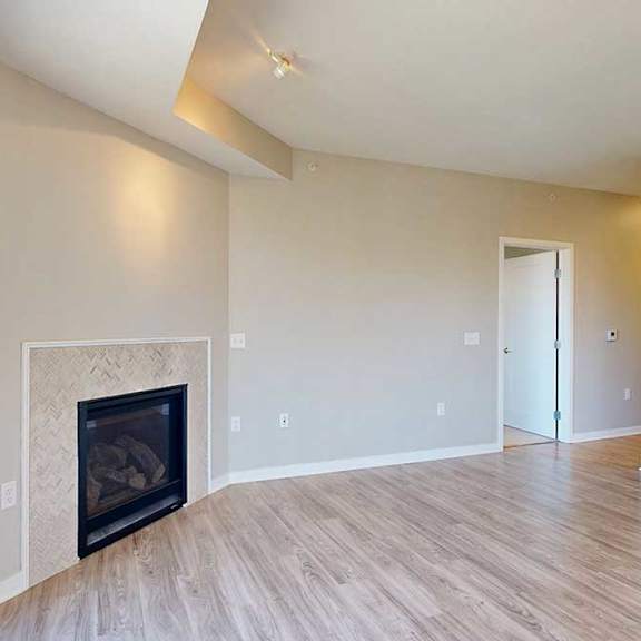 Thumbnail 18 of 29 A spacious living room with hardwood-style flooring and a built-in fireplace.