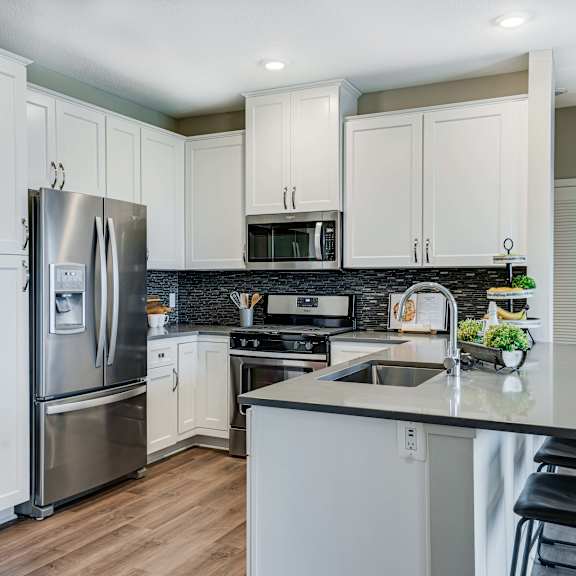 Thumbnail 4 of 19 Premium kitchen featuring dark quartz countertops and white cabinetry in a two bedroom penthouse Princeton floor plan
