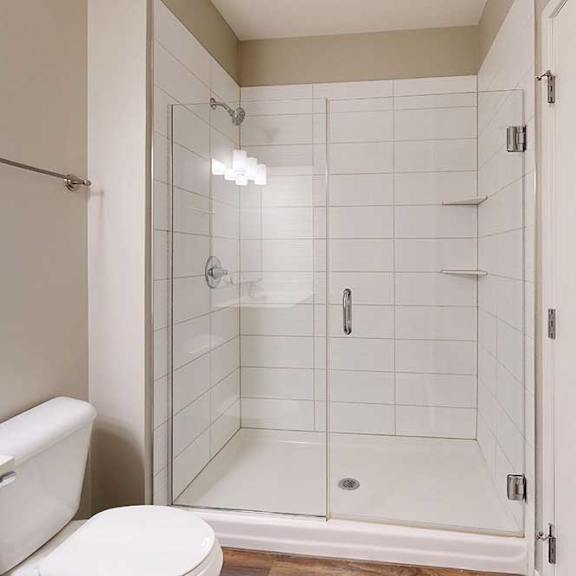 Thumbnail 12 of 13 A modern bathroom with a tiled walk-in shower and a glass door.