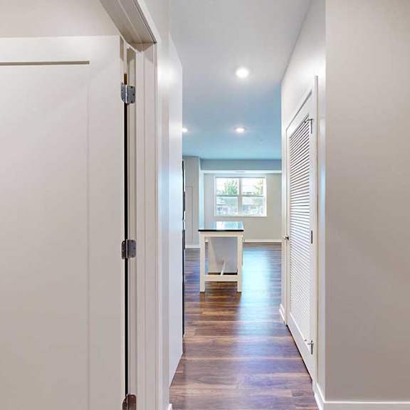 Thumbnail 2 of 13 A hallway leading from the front entryway to the open kitchen and living area.