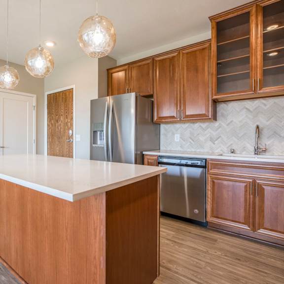 Thumbnail 5 of 12 A kitchen with wooden cabinets and a white island.