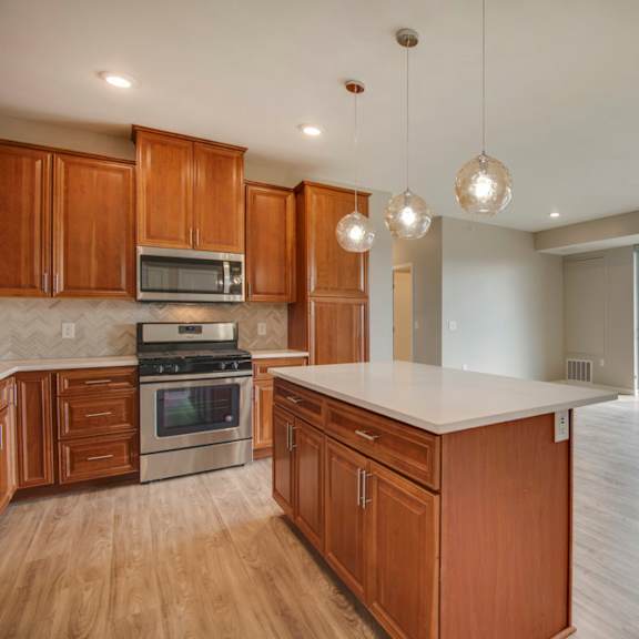 Thumbnail 2 of 12 A kitchen with wooden cabinets and a white countertop.