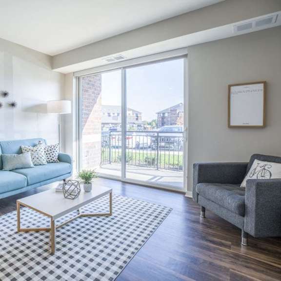 Thumbnail 6 of 12 An apartment living room with a blue couch and a glass sliding door