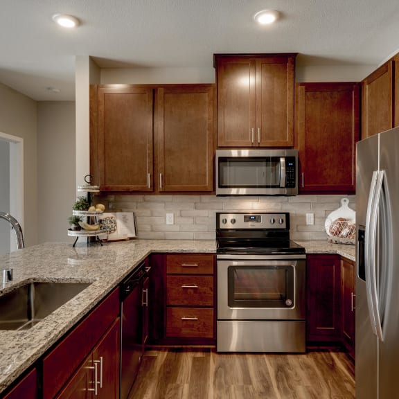 Thumbnail 5 of 19 Luxury apartment with dark cabinetry and granite countertops at Ascend at Woodbury MN 55129 new luxury apartments