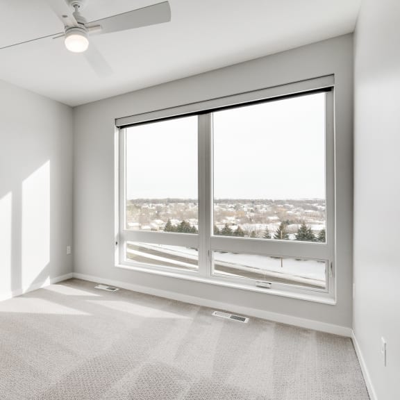 Thumbnail 14 of 16 Spacious luxury bedroom with large window and ceiling fan at Aspire at CityPlace in Woodbury, Minnesota