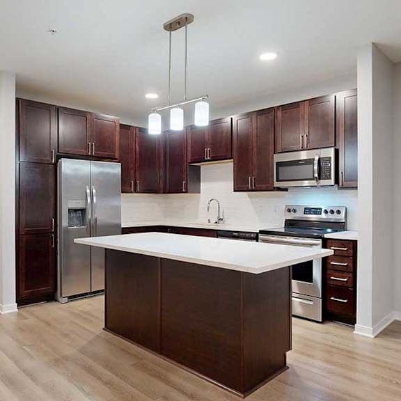 Thumbnail 6 of 19 A modern kitchen with dark wood cabinets and stainless steel appliances.