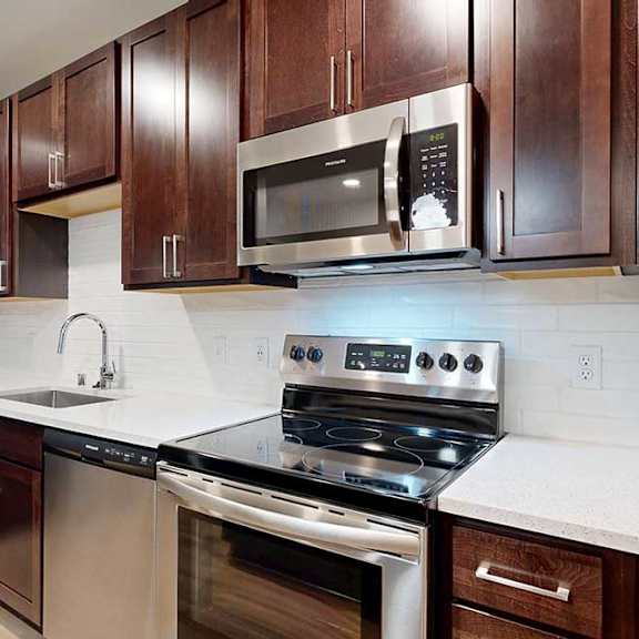 Thumbnail 3 of 19 A modern kitchen with dark wood cabinets and stainless steel appliances.