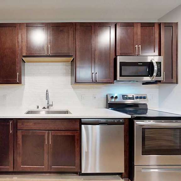 Thumbnail 4 of 19 A kitchen with brown cabinets and stainless steel appliances.