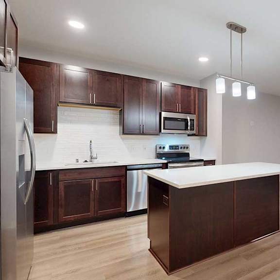 Thumbnail 7 of 19 A kitchen with brown cabinets and a white counter.