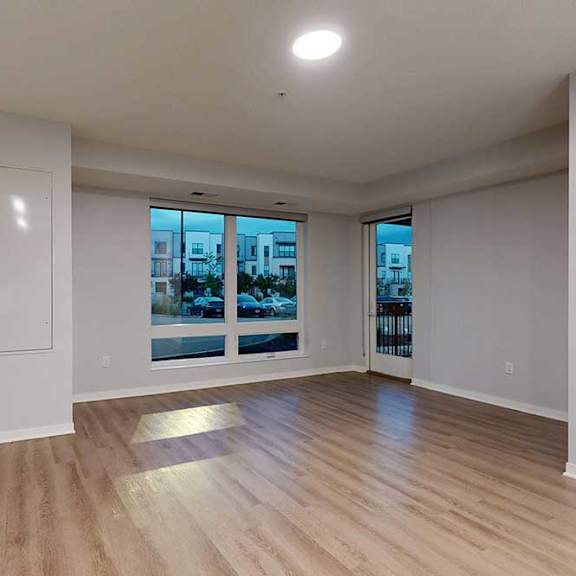 Thumbnail 16 of 19 A spacious room with wooden flooring and a large window overlooking a cityscape.