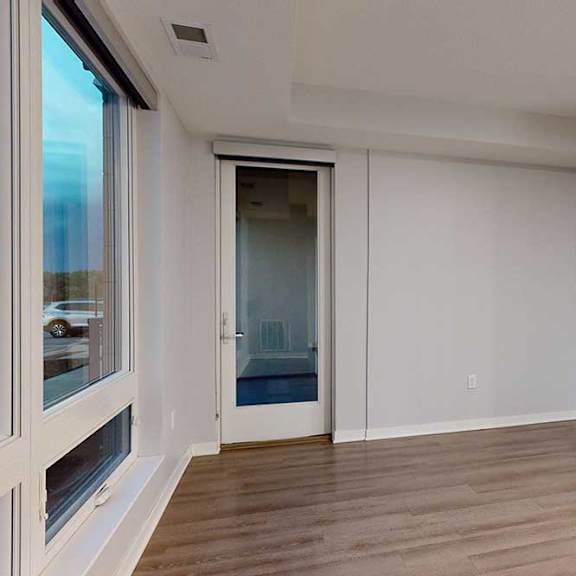 Thumbnail 10 of 19 A room with a wooden floor and a sliding glass door.