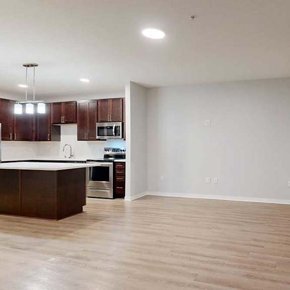 Thumbnail 9 of 19 A spacious kitchen with dark wood cabinets and a white countertop.