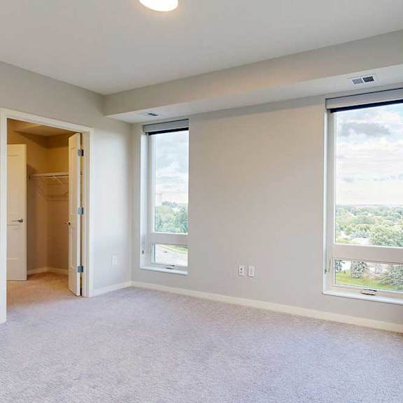 Thumbnail 21 of 27 A spacious room with a large window and a door leading to another room.