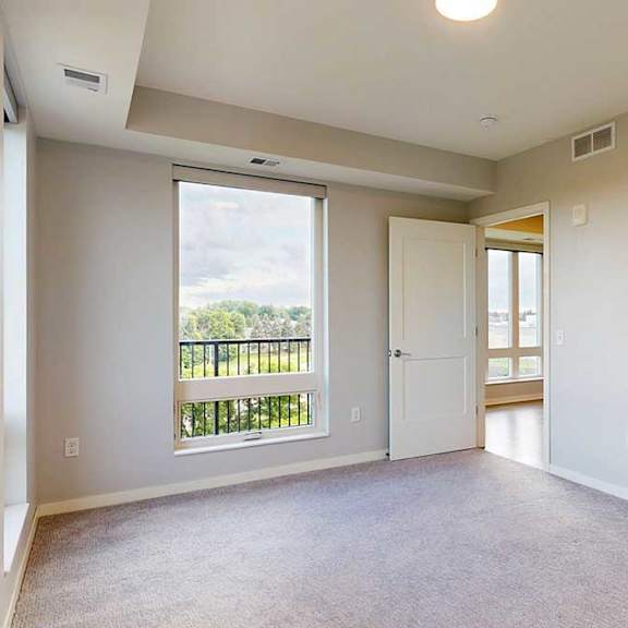 Thumbnail 19 of 27 A large empty room with a view of a balcony through a window.