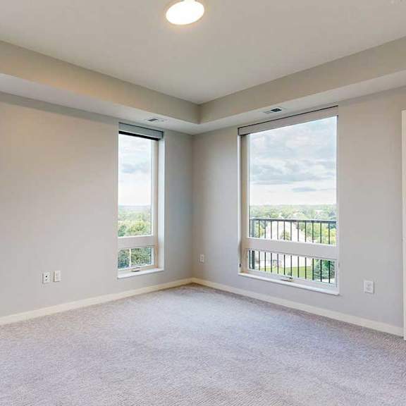 Thumbnail 4 of 27 A room with a carpet floor and three windows.