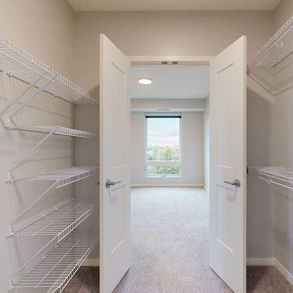 Thumbnail 9 of 27 A white walk-in closet with shelves and doors.