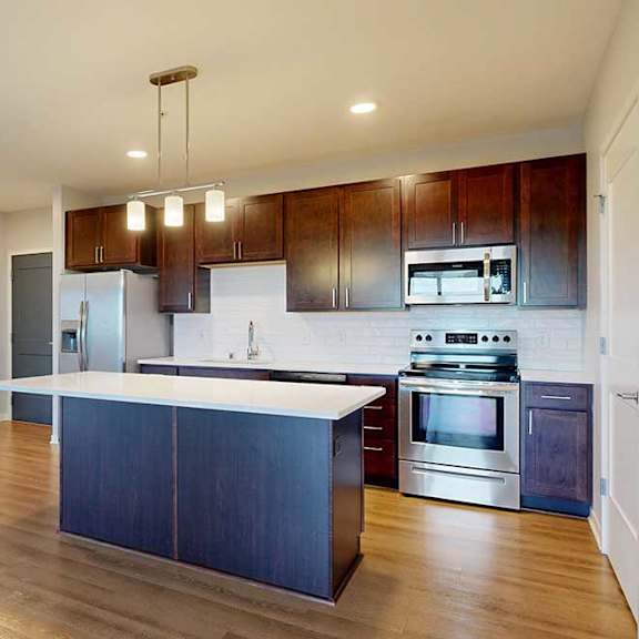 Thumbnail 12 of 27 A kitchen with dark wood cabinets and stainless steel appliances.