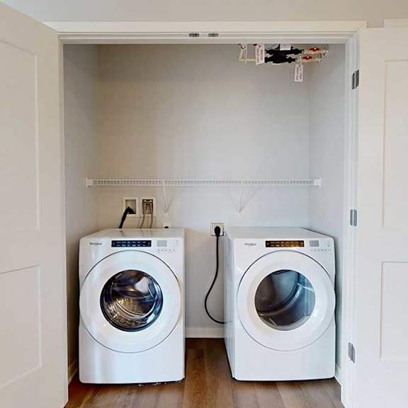 Thumbnail 10 of 27 Two white front loading washing machines in a small laundry room.