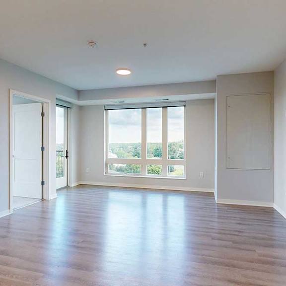 Thumbnail 20 of 27 A spacious room with wooden floors and large windows.
