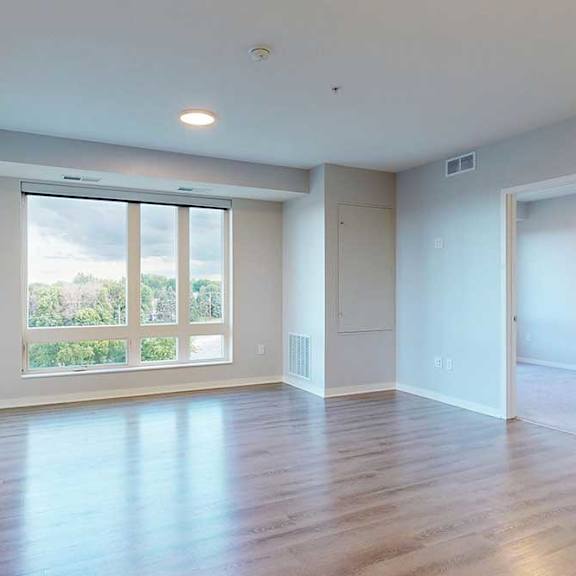 Thumbnail 3 of 27 A large empty room with wooden floors and a sliding glass door.