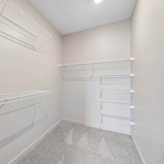 Thumbnail 15 of 17 Walk-in closet with multiple wire shelving systems, carpet flooring, and ample storage space for clothing and household items.