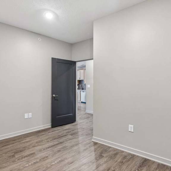 Thumbnail 11 of 17 Flexible den or home office space with wood-look flooring, neutral walls, and an open layout connected to the main living area.