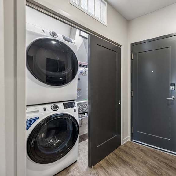 Thumbnail 16 of 17 In-home laundry area with a stacked washer and dryer, wood-look flooring, and convenient access from the main living space.