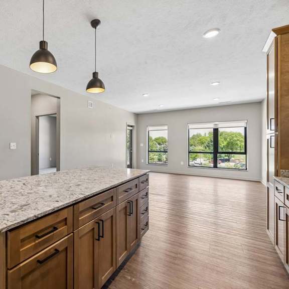 Thumbnail 5 of 17 Open living and dining area overlooking the kitchen, featuring a large island, pendant lighting, and expansive windows for natural light.