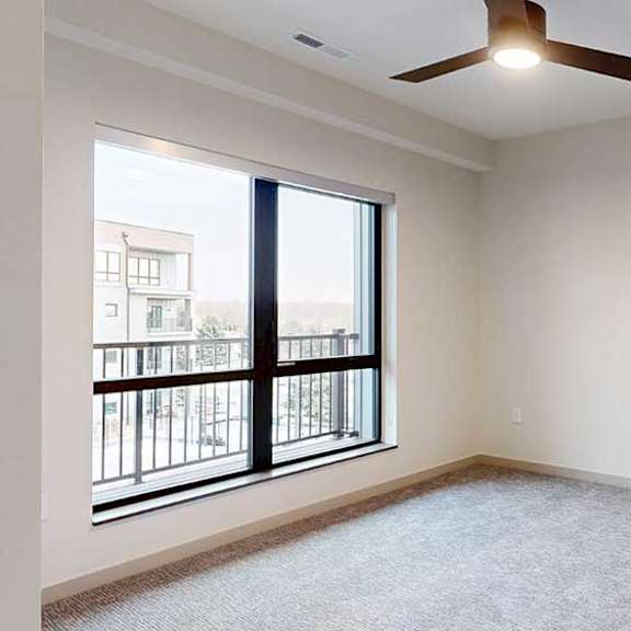 Thumbnail 21 of 29 a bedroom with a large window, a ceiling fan, and carpeted flooring
