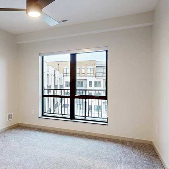 Thumbnail 20 of 29 a bedroom with a large window looking out to the balcony and a ceiling fan