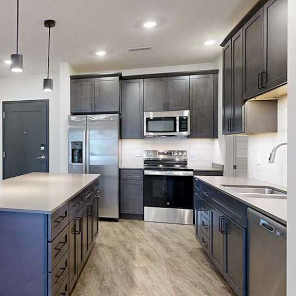 Thumbnail 16 of 29 a modern kitchen with dark wooden cabinets, stainless steel appliances, quartz countertops, and a large central island