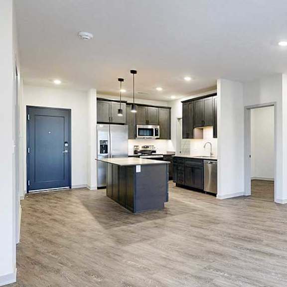 Thumbnail 15 of 29 an open-concept living room and kitchen with hardwood flooring, dark wooden cabinets, and quartz countertops