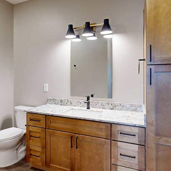 Thumbnail 23 of 29 a bathroom with a light brown cabinets, a tall storage cabinet, quartz vanity sink, a mirror, and a shower and tub